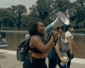 Reflecting on racial reckoning. A black marches with others while speaking into a megaphone.