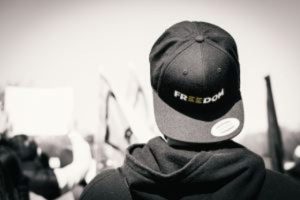 A person wearing a hat that says "Freedom" during a protest march.