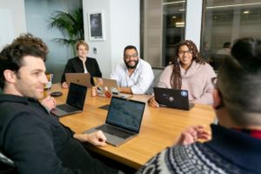 An inclusive meeting with employees gathered around an office table.